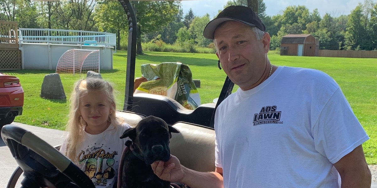 Father and daughter in kart posing with puppy.